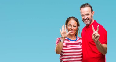 Orta yaş İspanyol çift aşık gösterilen ve parmakları ile işaret izole arka plan üzerinde kendinden emin ve mutlu gülümseyerek süre yedi numara.