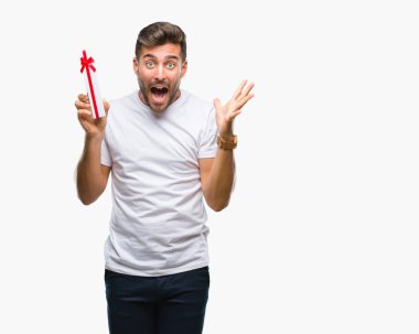 Sevgililer günü hediyesi üzerinde kocaman bir gülümseme ile çığlık zaferini kutluyor ve ellerini kaldırdı izole arka plan çok mutlu ve heyecanlı, kazanan ifade veren aşık genç yakışıklı adam