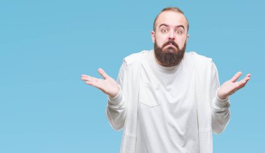 Spor kıyafetlerle üzerinde genç beyaz hipster adam arka plan clueless ve şaşkın bir ifadeyle kollar ve eller kaldırdı izole. Şüphe kavramı.