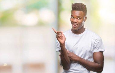 Kameraya bakarak yan el ve parmak ile işaret eden genç Afro-Amerikan adam yüzünde kocaman bir gülümseme ile izole arka plan üzerinde.