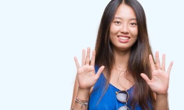 Genç Asyalı kadın gösterilen ve parmakları ile işaret izole arka plan üzerinde kendinden emin ve mutlu gülümseyerek süre on numara.