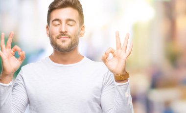 Yakışıklı delikanlı izole arka plan üzerinde dinlenmek ve gülümseyen gözlerle parmak ile meditasyon jest yapıyor kapalı. Yoga kavramı.
