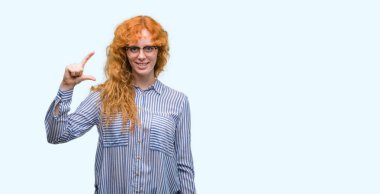 Gülümseyen genç redhead bussines kadın ve süre seyir ve kamera boyutu işaret parmaklarıyla yapıyor el ile kendine güvenen el hareketi. Ölçü kavramı.
