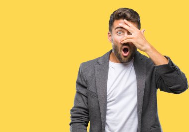 Mahcup ifadeyle parmaklarımın arasından seyir yüz ve gözler el ile kapsayan şok izole arka plan bakmak üzerinde genç yakışıklı iş adamı.