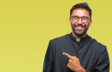 Yetişkin İspanyol Katolik rahip adam izole arka neşeli bir gülümseme ile el ve parmak kadar kameraya bakarak yüzündeki mutlu ve doğal ifade ile yan ile işaret eden yüz.