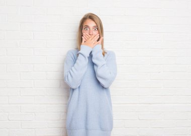 Güzel genç kadın beyaz tuğla duvar eller için hata ile ağız kapsayan şok yüzünden. Gizli kavramı.