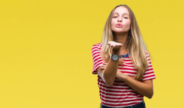 Genç güzel sarışın kadın izole arka plan bir öpücük el ile güzel ve seksi olmak hava üfleme kamera bakıyor. Aşk ifade.