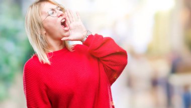 Kazak ve gözlük bağırarak ve ağzı üzerinde el ile yan için çığlık izole arka plan üzerinde giyen genç güzel sarışın kadın. İletişim kavramı.