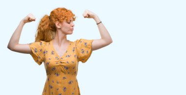 Kol kasları gururlu gülümseyen gösterilen genç Kızıl saçlı kadın. Fitness kavramı.