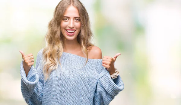 El ile pozitif jest yapıyor izole arka plan başarı işareti üzerinde kış kazak giyen güzel genç sarışın kadın başparmak gülümseyen ve mutlu. Neşeli bir ifadeyle, kazanan jest kameraya bakıyor.