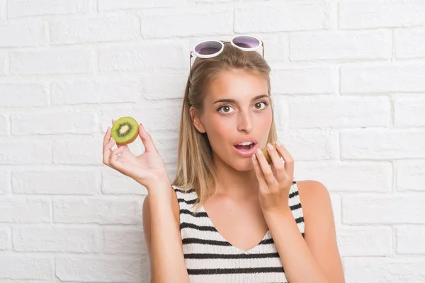 Hermosa Mujer Joven Sobre Pared Ladrillo Blanco Comer Kiwi Verde — Foto de Stock