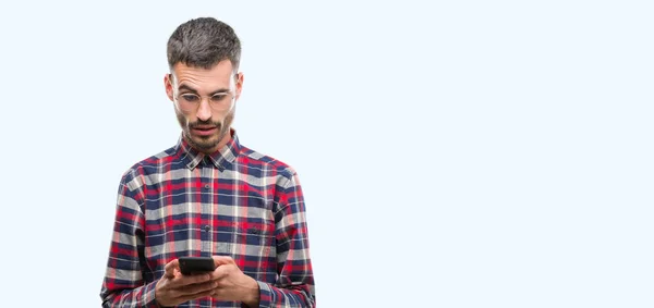 Homem Adulto Jovem Hipster Segurando Smartphone Assustado Choque Com Rosto — Fotografia de Stock