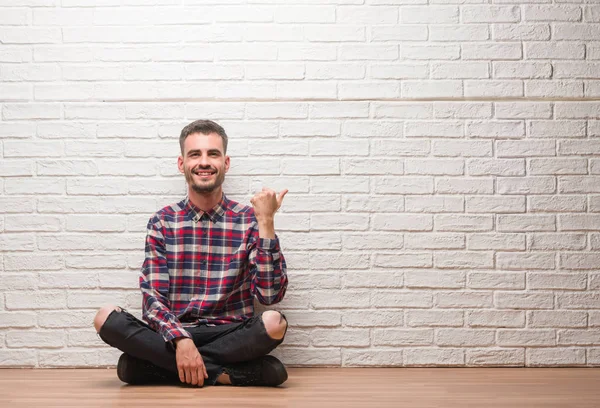 Joven Hombre Adulto Sentado Sobre Pared Ladrillo Blanco Señalando Mostrando — Foto de Stock