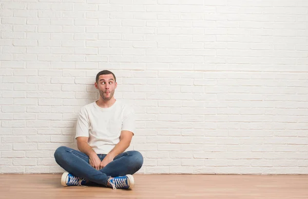 Young Caucasian Man Sitting Floor White Brick Wall Making Fish — Stock Photo, Image