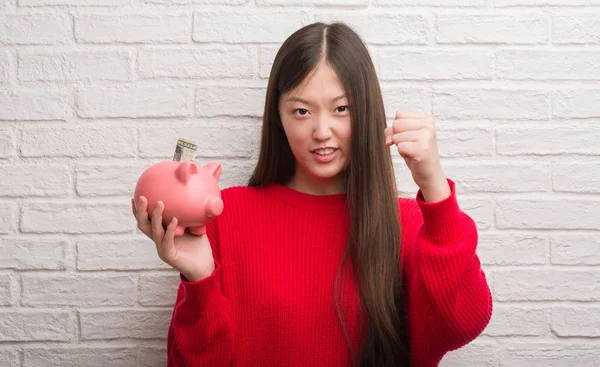 Young Chinese Woman Brick Wall Holding Piggy Bank Annoyed Frustrated — Stock Photo, Image