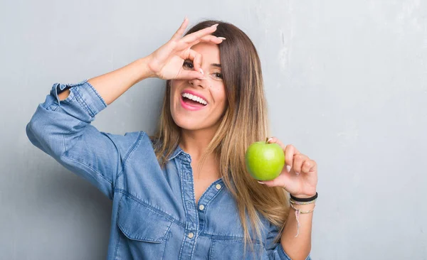 Giovane Donna Adulta Sopra Grigio Grunge Muro Mangiare Mela Verde — Foto Stock