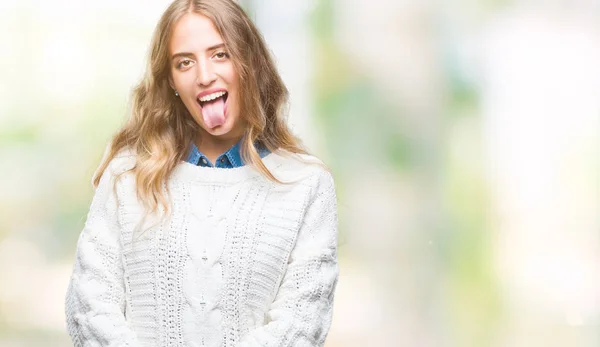 舌を付着分離の背景に冬のセーターを着ている美しい若いブロンドの女性を面白い表現に満足 感情の概念 — ストック写真