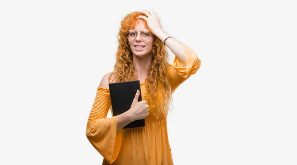 Young Redhead Student Woman Holding Book Stressed Hand Head Shocked — Stock Photo, Image