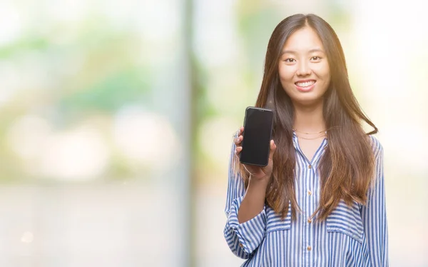 Young asian woman showing blank screen of smartphone over isolated background with a happy face standing and smiling with a confident smile showing teeth