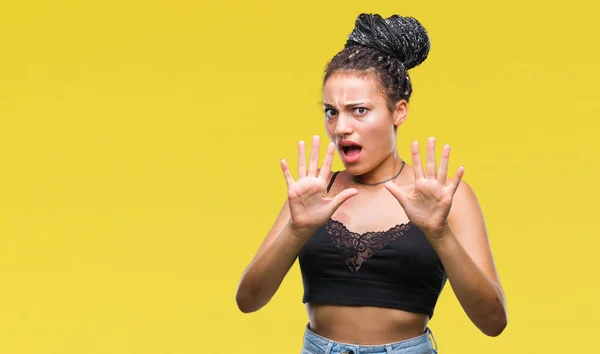 Young braided hair african american with pigmentation blemish birth mark over isolated background afraid and terrified with fear expression stop gesture with hands, shouting in shock. Panic concept.