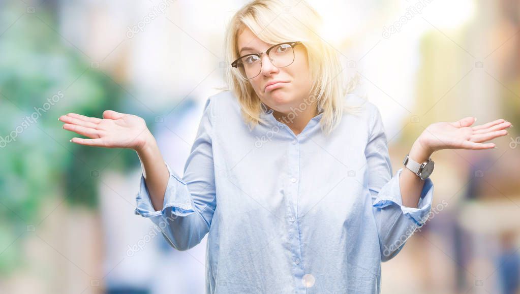 Young beautiful blonde business woman wearing glasses over isolated background clueless and confused expression with arms and hands raised. Doubt concept.