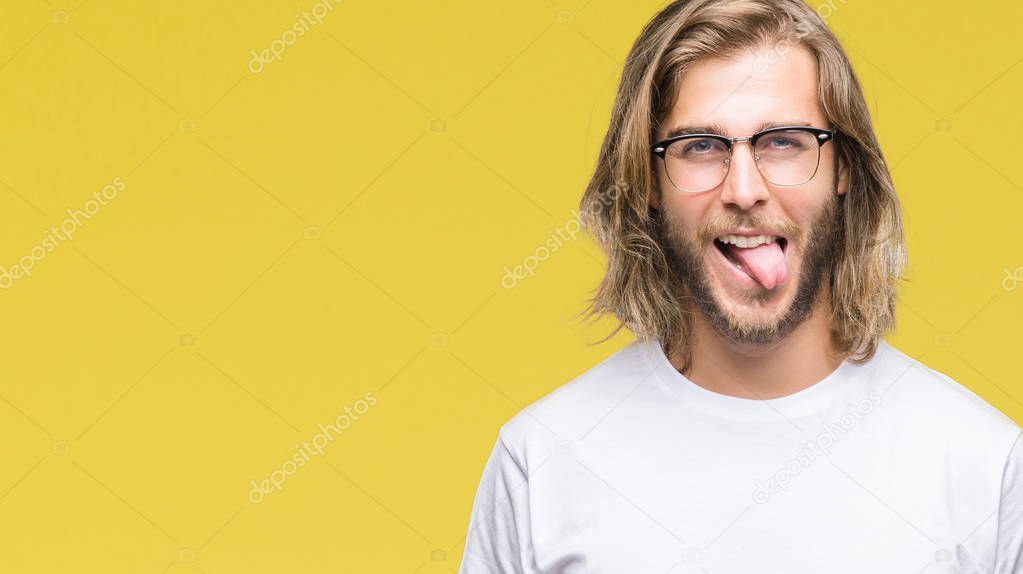 Young handsome man with long hair wearing glasses over isolated background sticking tongue out happy with funny expression. Emotion concept.