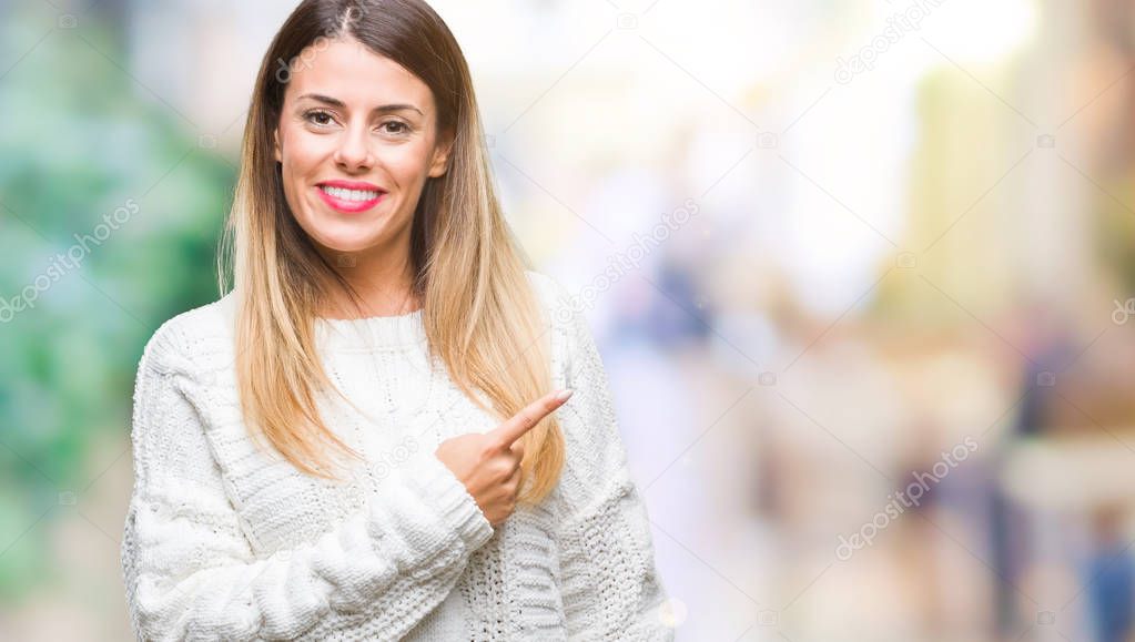 Young beautiful woman casual white sweater over isolated background cheerful with a smile of face pointing with hand and finger up to the side with happy and natural expression on face looking at the camera.