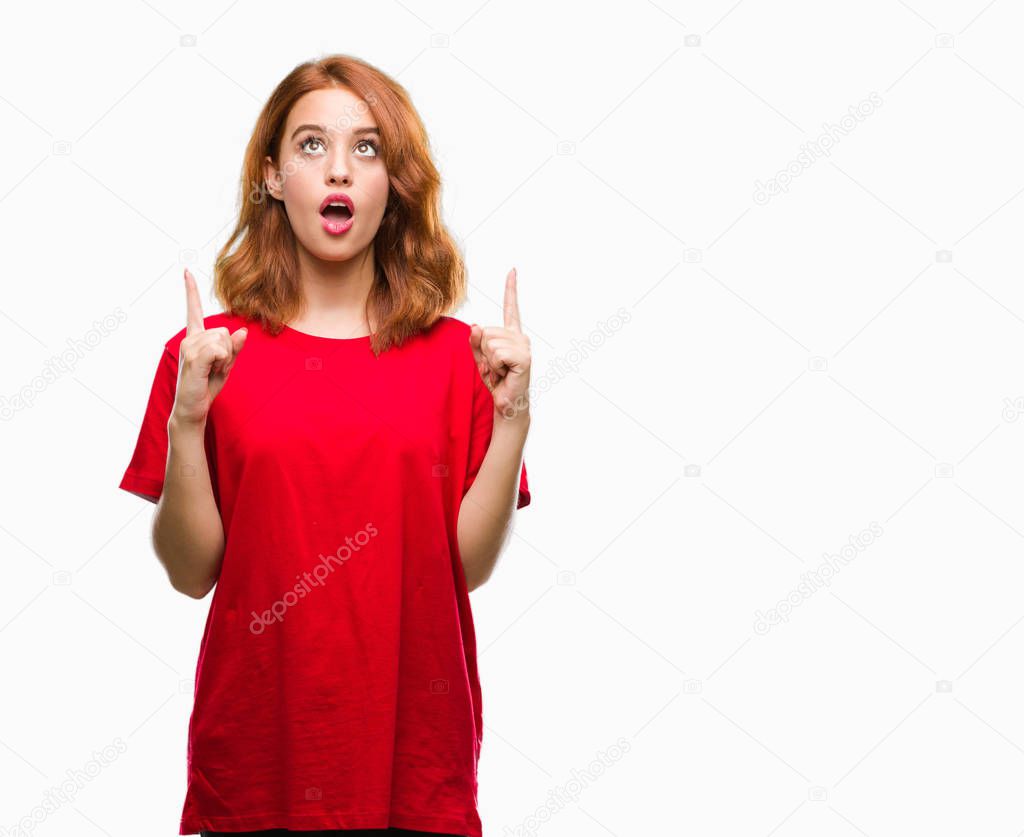 Young beautiful woman over isolated background amazed and surprised looking up and pointing with fingers and raised arms.