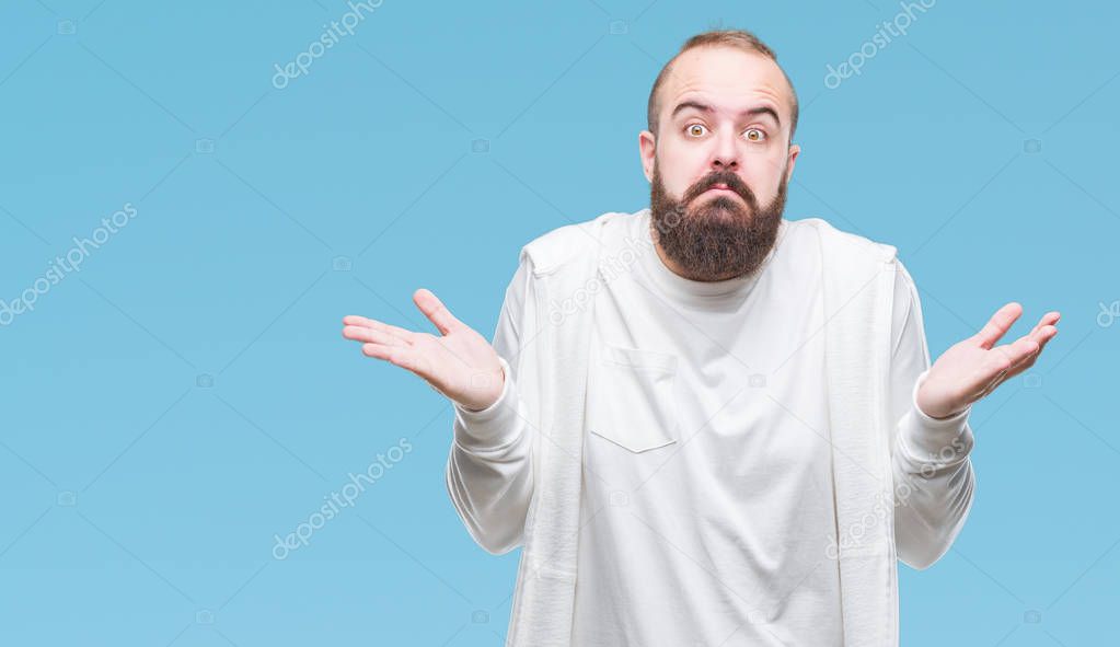 Young caucasian hipster man wearing sport clothes over isolated background clueless and confused expression with arms and hands raised. Doubt concept.