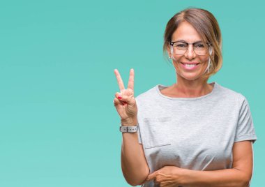 Mutlu yüz zafer işareti yaparken kameraya göz kırpıyor ile gülümseyen izole arka plan üzerinde gözlük takan orta yaş İspanyol kadın kıdemli. İki numaralı.