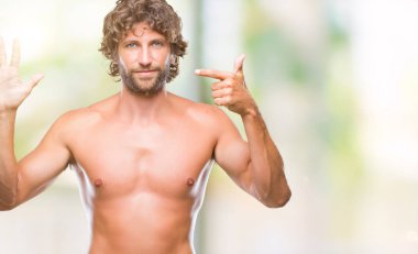 Yakışıklı İspanyol modeli adam seksi ve gömleksiz gösterilen ve parmakları ile işaret izole arka plan üzerinde kendinden emin ve mutlu gülümseyerek süre yedi numara.