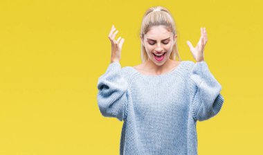 Kadın giyiyor kış kazak kızgın ve silah ile başarı için deli kutluyor izole arka plan üzerinde kaldırdı ve heyecanlı çığlık gözleri kapalı genç güzel sarışın ve mavi gözlü. Kazanan kavramı