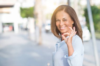 Güzel orta yaş İspanyol kadın parmakları, mükemmel sembolü olan ok işareti yapıyor güneşli bir sokak City