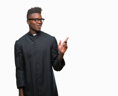 Kameraya bakarak yan el ve parmak ile işaret eden genç Afro-Amerikan rahip adam yüzünde kocaman bir gülümseme ile izole arka plan üzerinde.