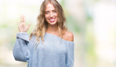 Güzel sarışın genç kadın giyiyor kış kazak gösterilen ve parmakları ile işaret izole arka plan üzerinde beş kendinden emin ve mutlu gülümseyerek iken numara.