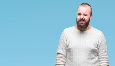 Seksi bir ifadeyle, neşeli ve mutlu yüzünü kameraya bakarak göz kırpıyor izole arka plan üzerinde kış kazak giyen genç beyaz hipster adam.