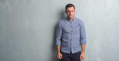 Gri grunge duvar şüpheci ve sinir, papatyanın üzgün sorun nedeniyle genç beyaz adam. Negatif kişi.