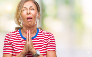 Orta yaş İspanyol kadın kıdemli yalvarıyor ve umut ifade yüzünde çok duygusal ve endişe ile birlikte elleriyle dua izole arka plan üzerinde. Bağışlanmak. Din kavramı.