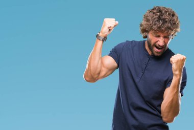 Gülümseyen ve başarı için çığlık yakışıklı İspanyol modeli izole arka plan çok mutlu ve heyecanlı kaldırdı, silah ile kazanan jest yapıyor adam. Kutlama kavramı.