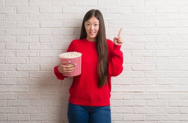 Tuğla Genç Çinli kadın pop Mısır bir fikirle sürpriz yemek duvar veya gülen yüz, bir numara ile işaret parmağı soru