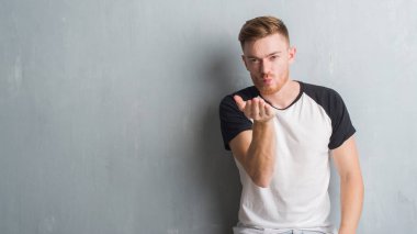 Bir öpücük el ile güzel ve seksi olmak hava üfleme kamera bakarak gri grunge duvarın üzerinden genç Kızıl saçlı adam. Aşk ifade.