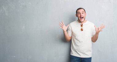 Gri grunge üzerinde beyaz delikanlı duvar giyen güneş gözlüğü deli ve çığlık kaldırdı ve açık gözleri heyecanlı silah ile başarı için hayran kutluyor. Kazanan kavramı