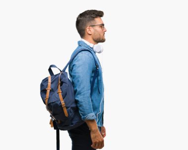 İzole arka tarafına, seyir üzerinde kulaklık ve sırt çantası giyen genç yakışıklı turist adam sakin ol kendine güvenen gülümseme ile doğal yüz pozuyla profili.