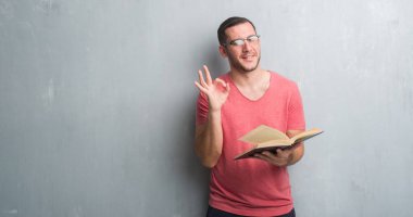 Parmak, mükemmel sembolü ile ok işareti yapıyor bir kitap okuma gri grunge duvarın üzerinden beyaz delikanlı