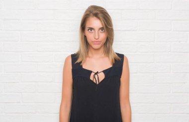 Güzel ve genç birbayan acımak yüz ciddi düşünüyorum üstünde kendine güvenen bir ifade ile beyaz tuğla duvarın üzerinden