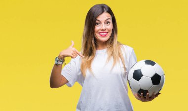 Sürpriz yüz işaret parmağı kendini izole arka plan üzerinde futbol topu tutan genç güzel kadın