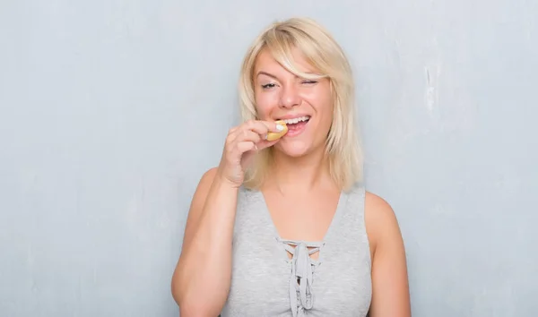 Adult Caucasian Woman Grunge Grey Wall Eating Macaron Confident Expression — Stock Photo, Image