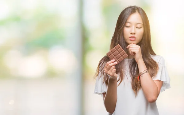 Junge Asiatische Frau Die Schokoriegel Über Isoliertem Hintergrund Isst Ernstes — Stockfoto