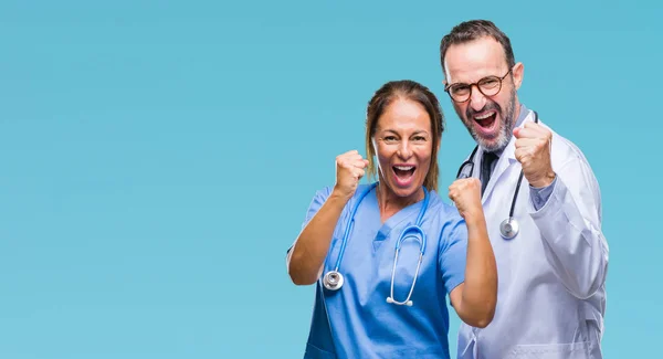 中年拉美裔医生伴侣夫妇穿医疗制服在孤立的背景非常高兴和兴奋做赢家手势举起双臂 微笑和尖叫的成功 庆典理念 — 图库照片
