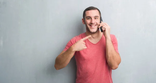 Jeune Homme Caucasien Sur Mur Gris Grunge Parler Téléphone Pointage — Photo